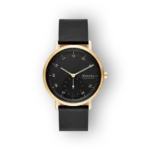 Arany színű tok, fekete számlap és bőrszíj jellemzi a Skagen karórát, elegáns és minimalista dizájnnal.