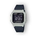 Fekete háttéren látható a Casio digitális karóra, ezüst színű tokban, fekete szilikon szíjjal, digitális kijelzővel és világítással.